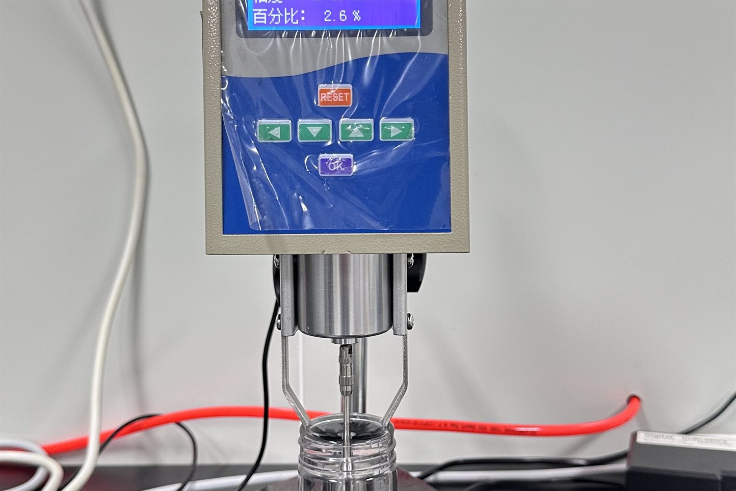 Digital force gauge — needle-to-hub pull-off strength measured to the gram.